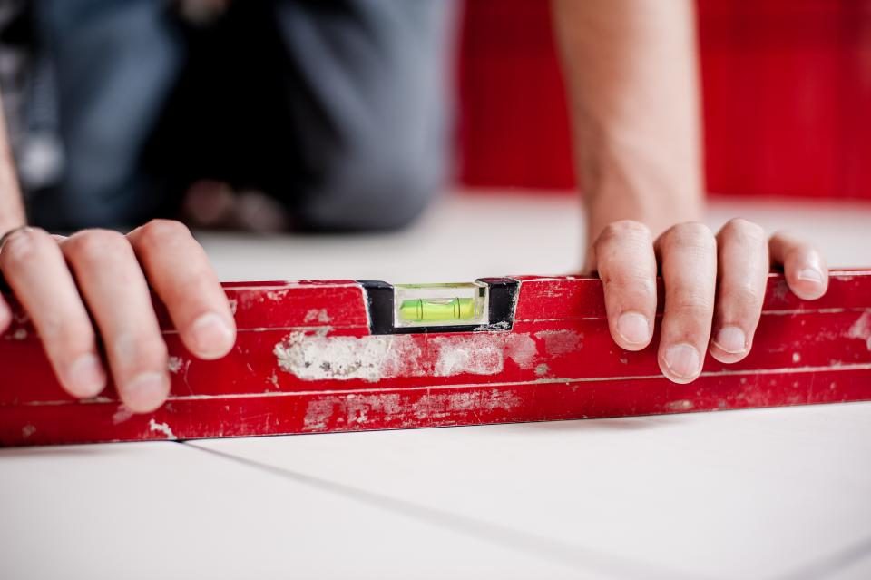 Hands setting a red spirit level on a flat surface to check that it's level