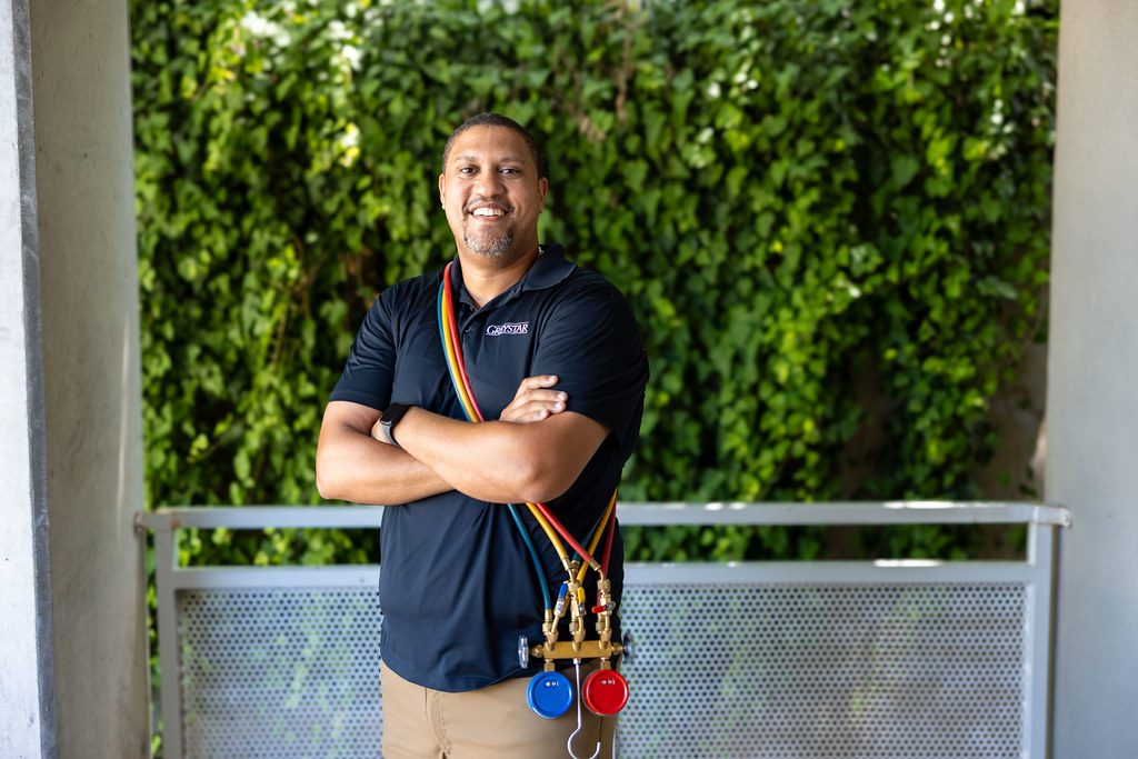 HVAC technician with red, yellow and blue manifold gauge hoses draped over the shoulder