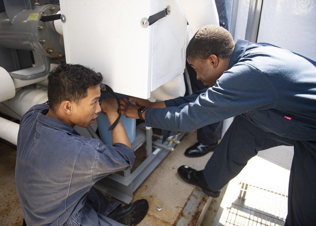Two technicians working on a large air handling unit